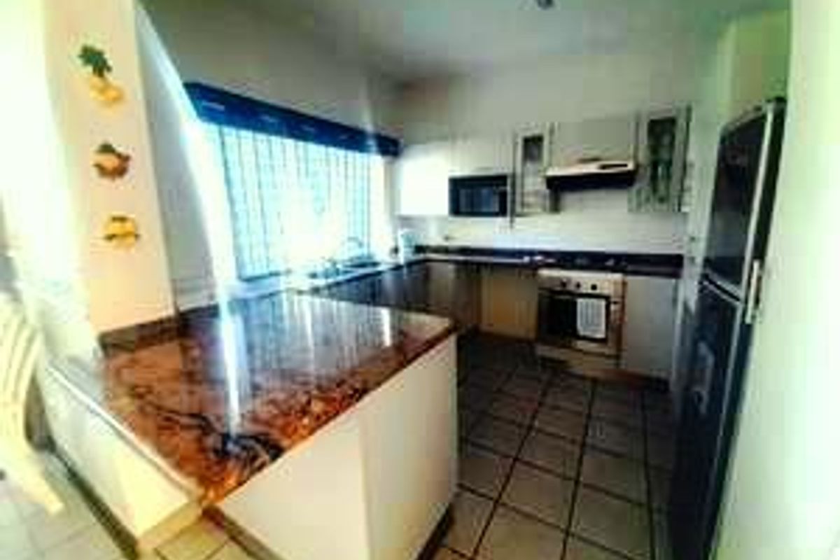 A functional kitchen featuring built-in cabinetry, laminate countertops, a built-in oven with extractor fan, and tiled flooring.