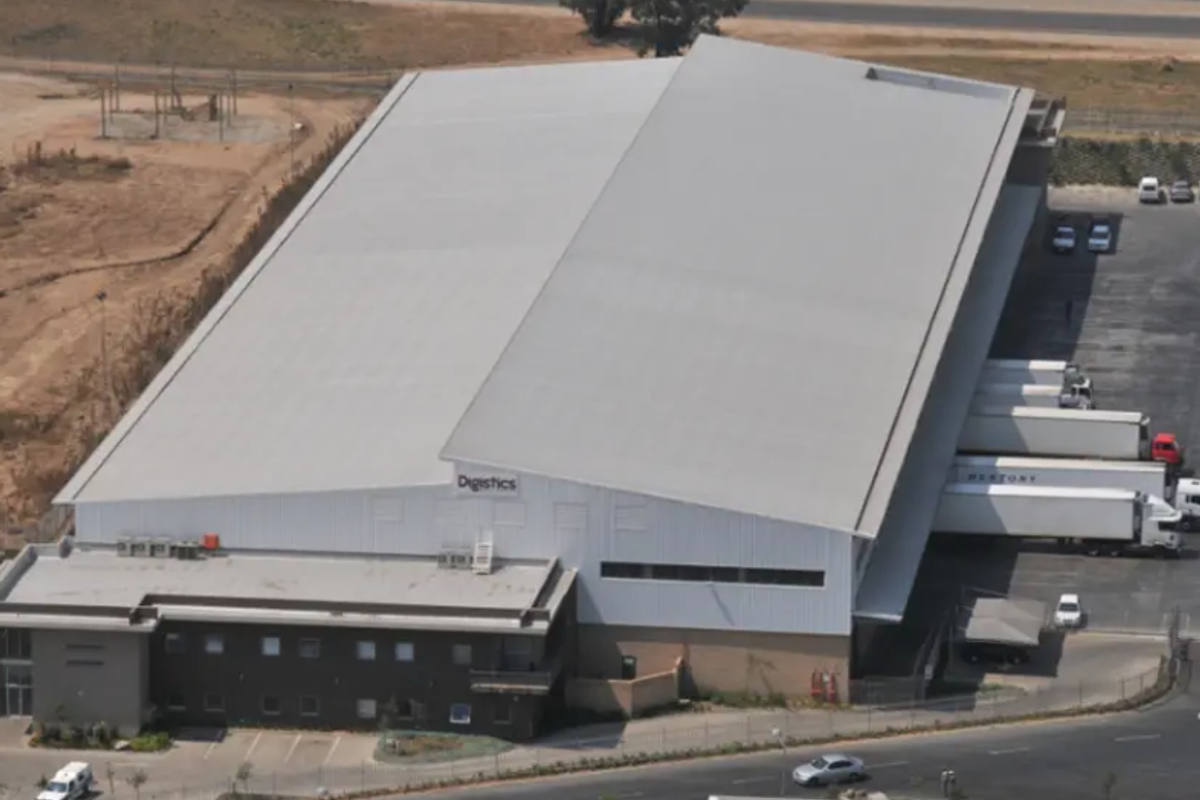 Aerial view of a large industrial warehouse facility featuring multiple loading docks, a spacious yard, and an attached office building.