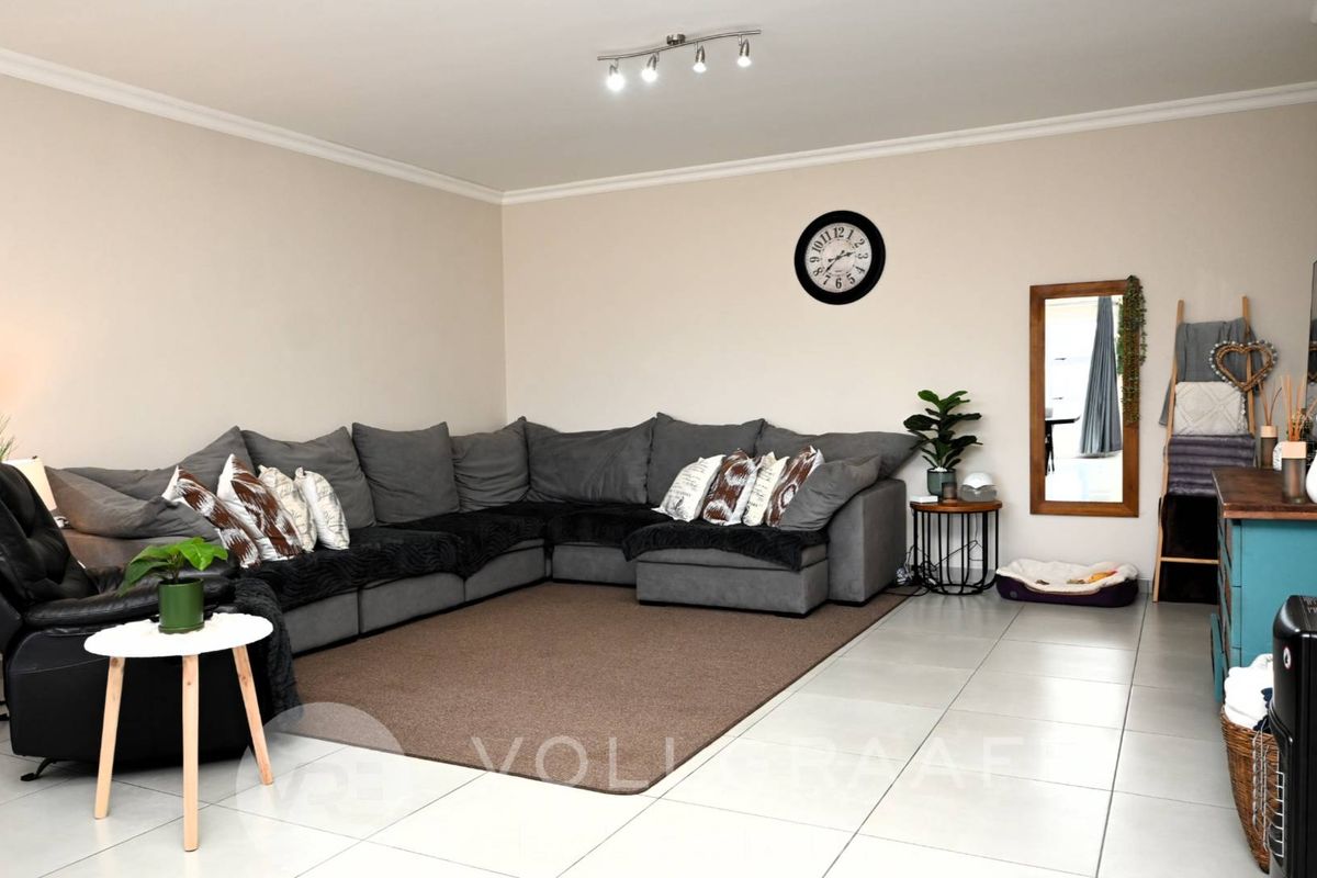Spacious living room featuring neutral tiled flooring, coved ceilings, and modern track lighting, providing a comfortable and well-maintained area for relaxation.