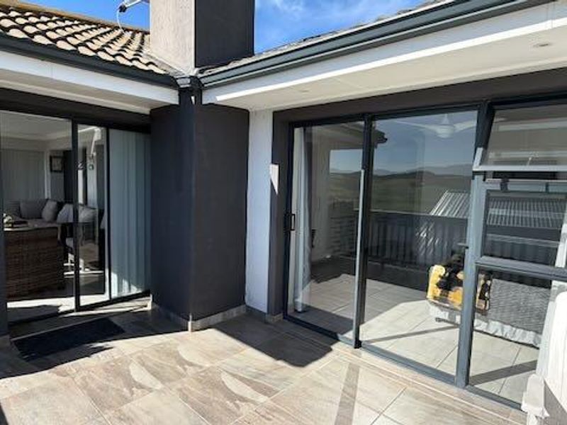 A covered patio area featuring modern tiled flooring, large sliding glass doors providing access to the interior, and recessed downlighting.