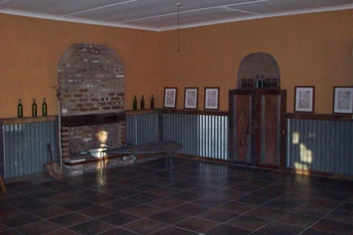 Spacious living area featuring a rustic brick fireplace, corrugated metal wall paneling, and dark tiled flooring.