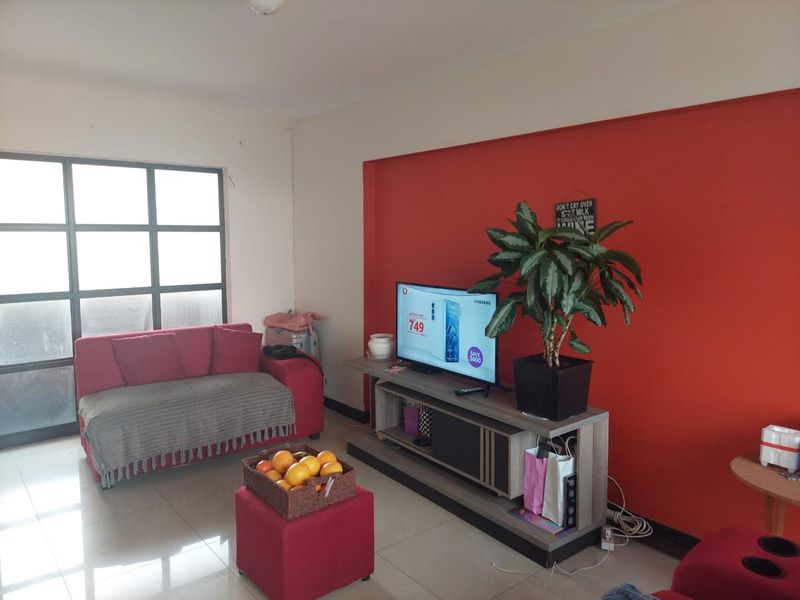 A living room featuring tiled flooring and a large grid-pattern window, providing natural light to the space.