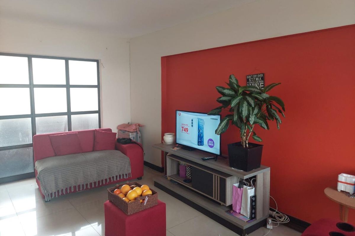 A living room featuring tiled flooring and a large grid-pattern window, providing natural light to the space.