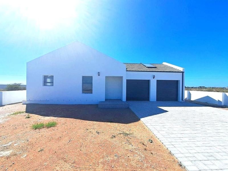 Front elevation of a modern single-story house featuring a double garage, paved driveway, and clean white exterior finish under a clear sky.