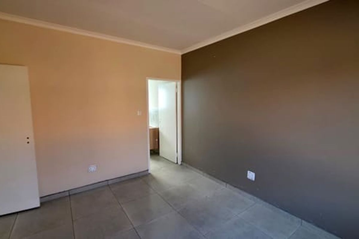 A vacant bedroom featuring tiled flooring, built-in cupboard, and a doorway leading to an adjacent room.