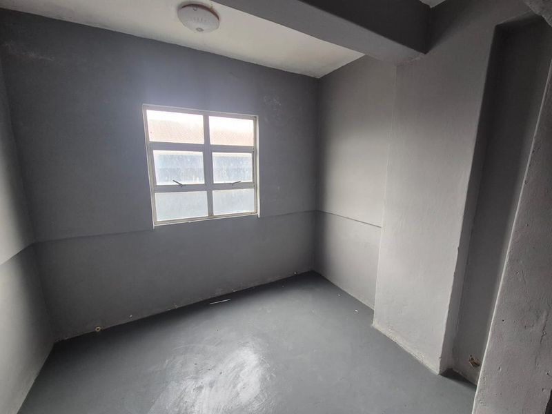 An empty bedroom featuring grey painted walls and flooring, providing a blank canvas for renovation or interior design updates.