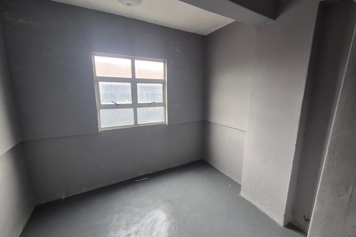 An empty bedroom featuring grey painted walls and flooring, providing a blank canvas for renovation or interior design updates.
