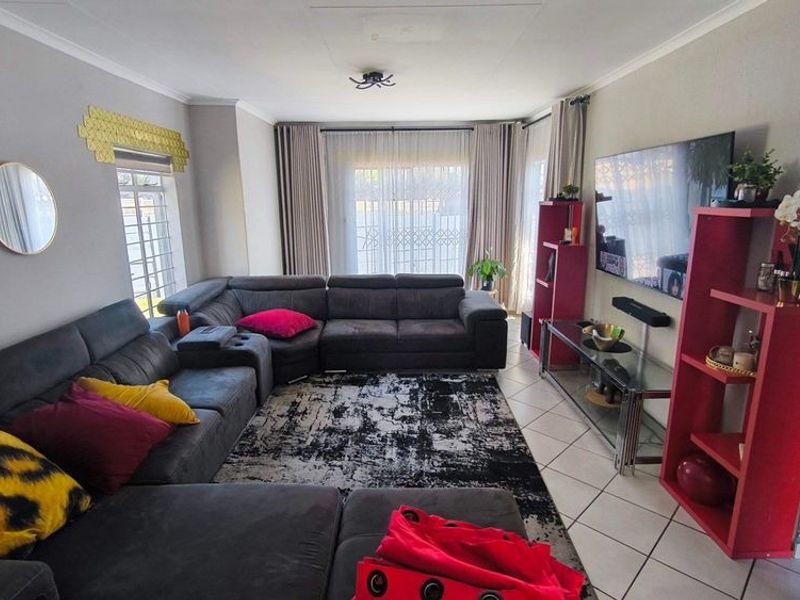 A comfortable living room featuring tiled flooring and large windows with curtain tracks, providing a bright and functional space for relaxation.