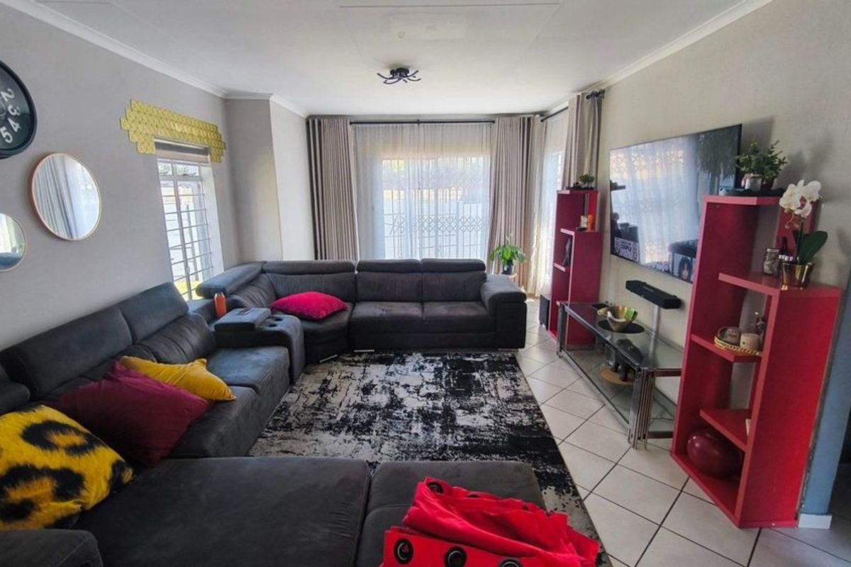 A comfortable living room featuring tiled flooring and large windows with curtain tracks, providing a bright and functional space for relaxation.