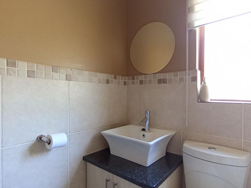 A compact bathroom featuring a modern vessel sink on a granite vanity, tiled splashback, and a neutral color palette.