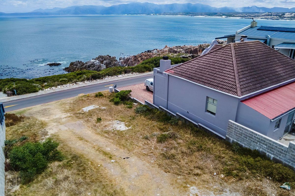 Aerial view of a vacant residential plot situated along the coastline, featuring direct ocean views and proximity to existing residential infrastructure.