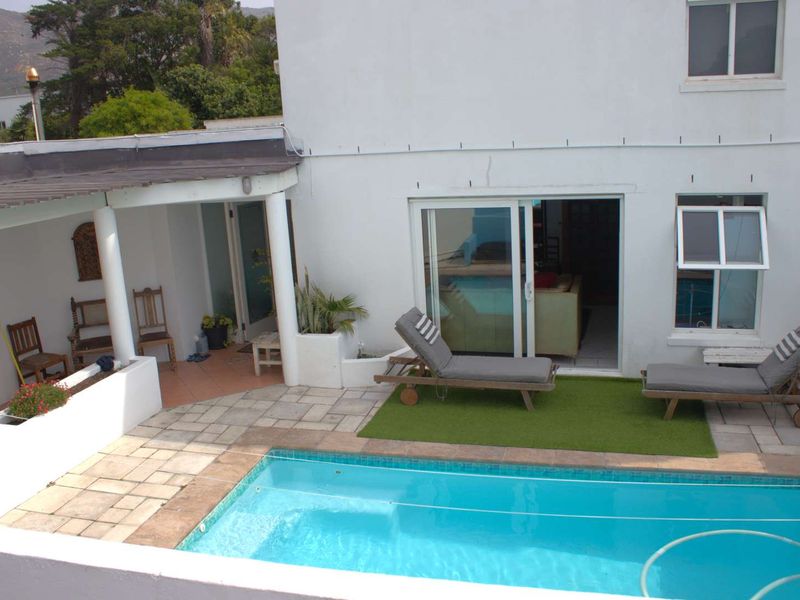 Outdoor pool area featuring a swimming pool, paved patio, and covered veranda with direct access to the interior living space via sliding glass doors.