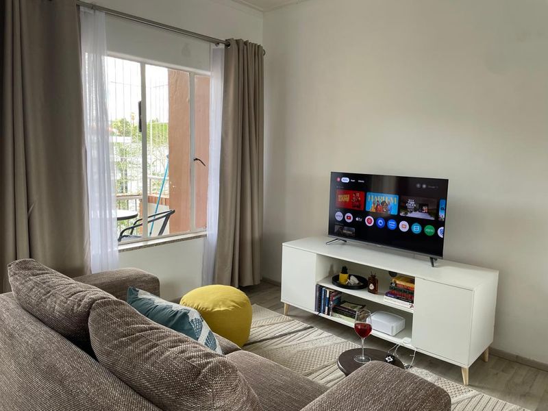 A comfortable living room featuring laminate flooring and a large window with natural light, providing a bright and inviting space.