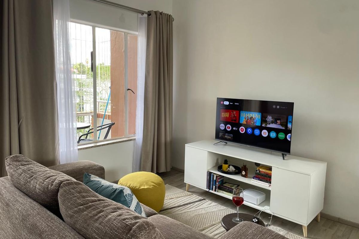 A comfortable living room featuring laminate flooring and a large window with natural light, providing a bright and inviting space.