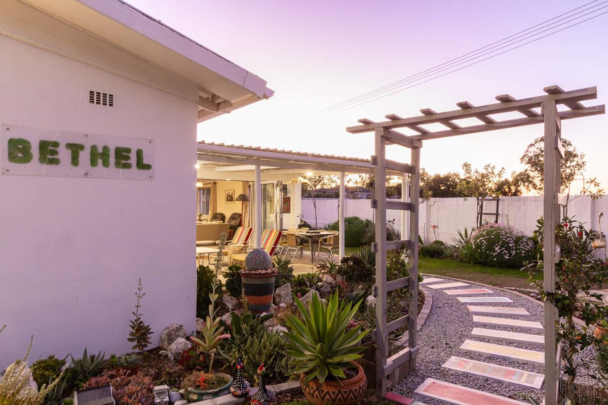 A charming rear garden featuring a paved walkway, wooden pergola, and a covered patio area, creating a peaceful outdoor living space.