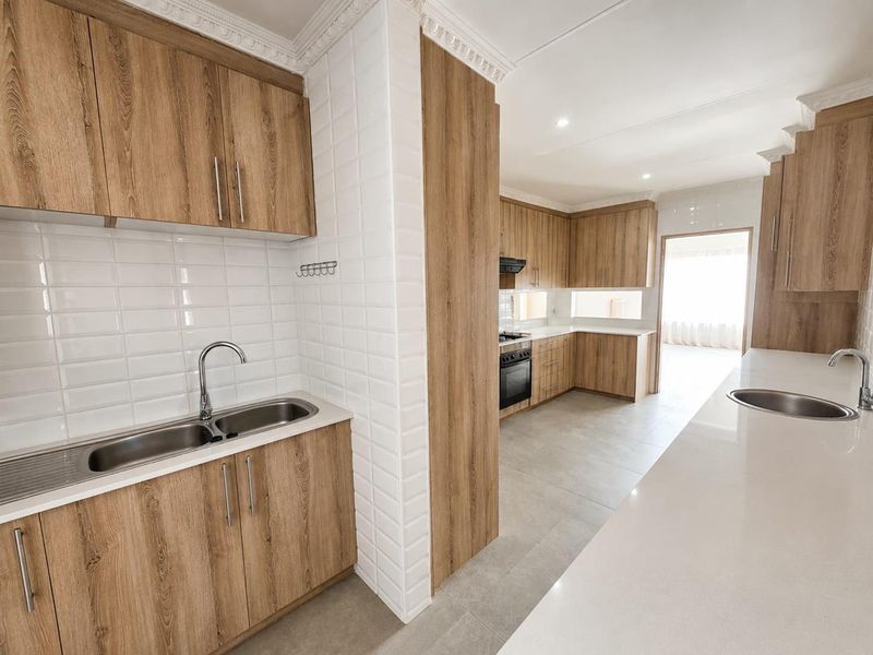 Modern kitchen featuring wood-look cabinetry, white subway tile backsplash, quartz countertops, and integrated appliances, offering a clean and functional workspace.