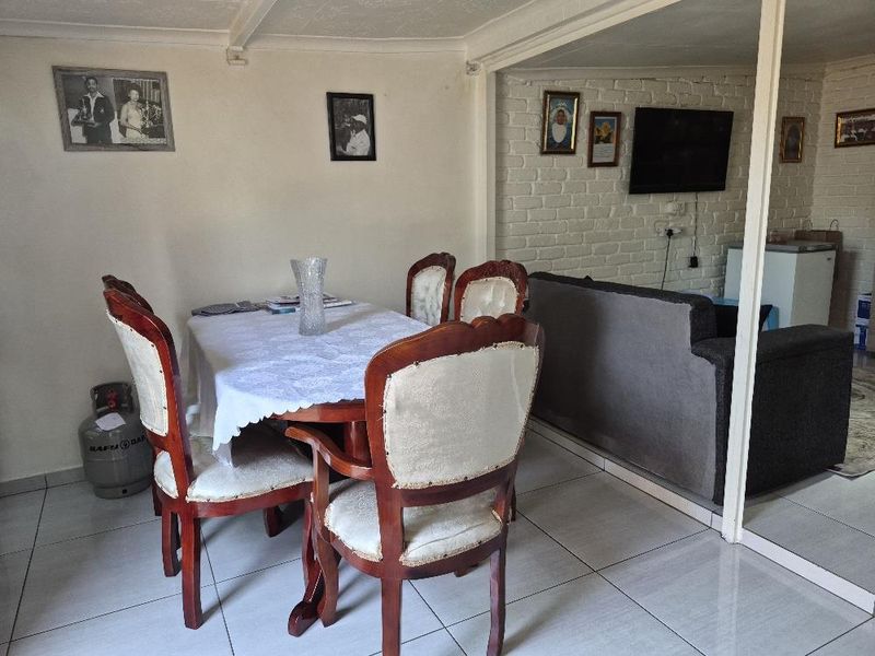 Open plan living and dining area featuring tiled flooring and a painted brick feature wall, offering a functional layout for daily living.