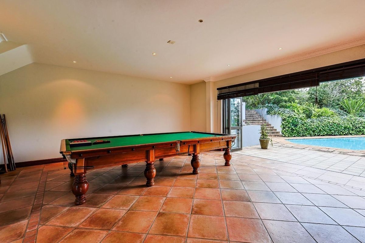 Spacious entertainment room featuring terracotta floor tiles and large folding doors opening directly onto a patio and swimming pool area.