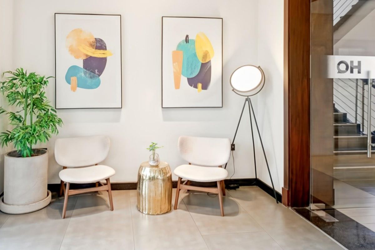 A bright and modern office entrance area featuring clean tiled flooring and a glass door with wooden framing.
