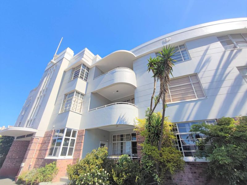 A well-maintained Art Deco apartment building featuring distinctive curved balconies, steel-framed windows, and a classic brick and stucco exterior facade.