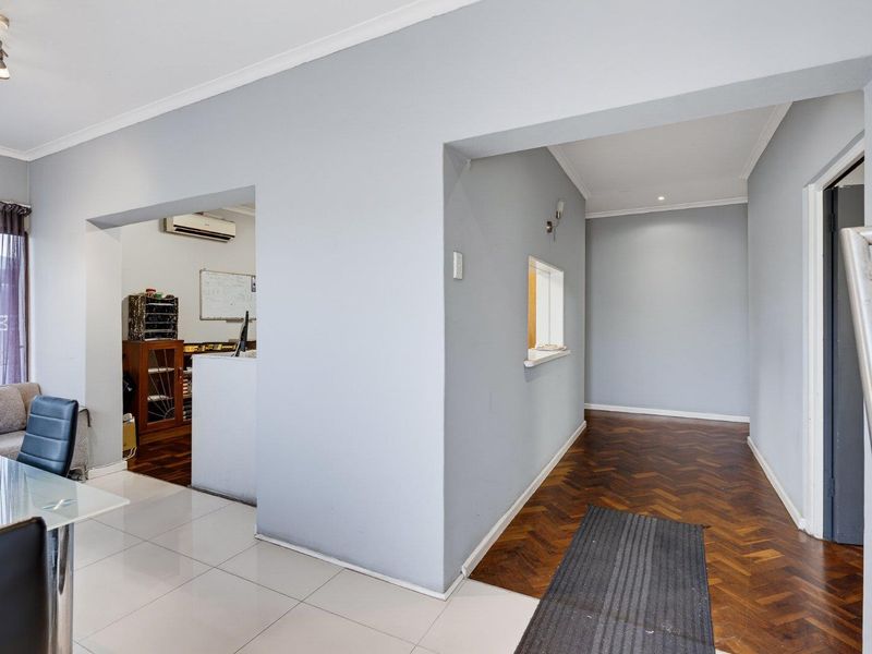 Open-plan living area featuring a blend of herringbone parquet and porcelain tile flooring, with a convenient pass-through window and split-system air conditioning.