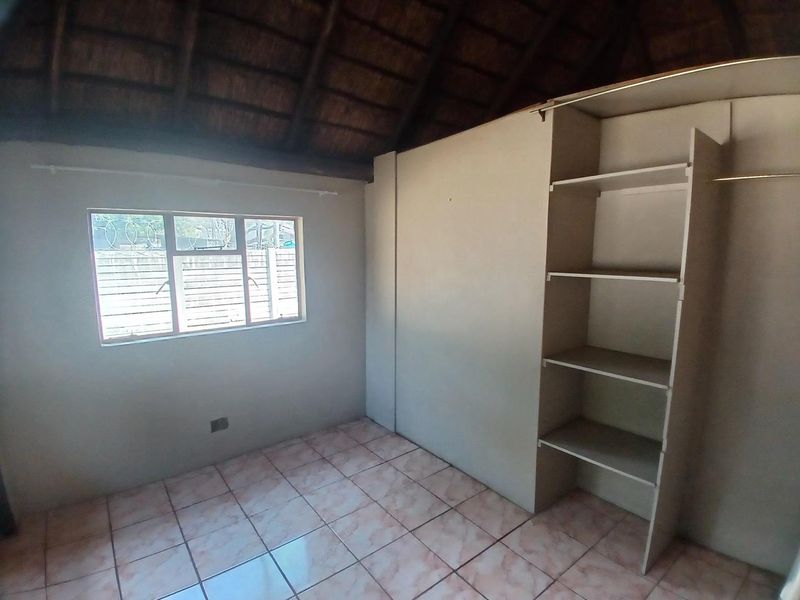 A bedroom featuring tiled flooring, a built-in wardrobe, and a traditional thatched roof ceiling.