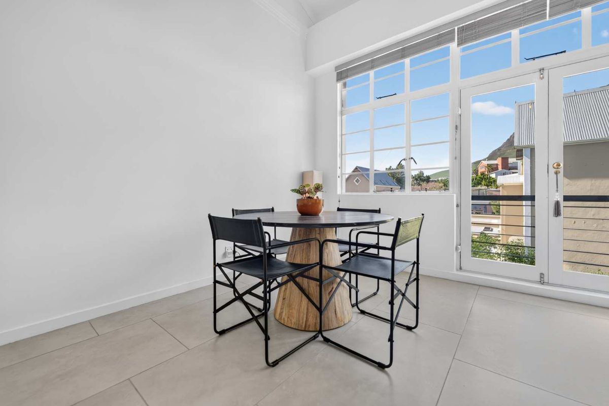 Bright living area featuring large windows and a glass door leading to a balcony, finished with neutral floor tiles and clean white walls.