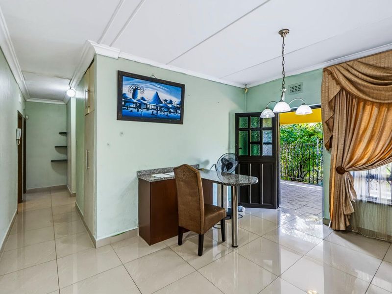 Living area featuring tiled flooring, built-in cabinetry with granite countertop, and direct access to an outdoor patio space.