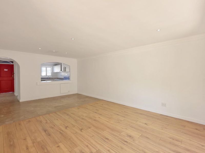 Spacious open-plan living area featuring a mix of laminate and tiled flooring, recessed lighting, and a convenient serving hatch connecting to the kitchen.