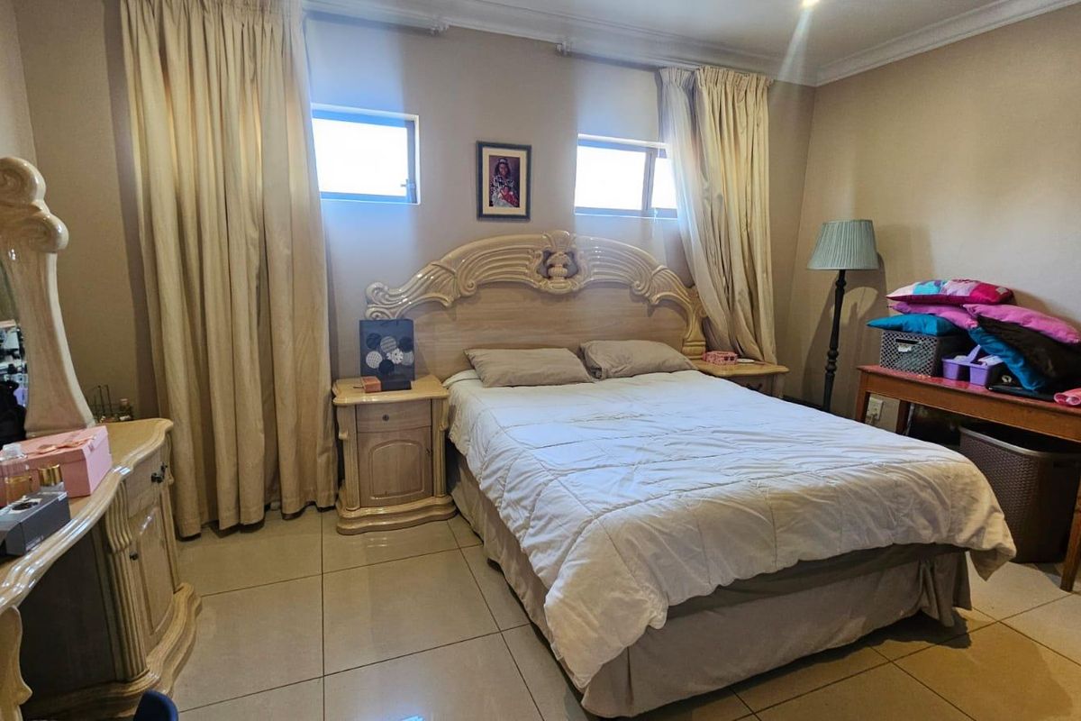 A spacious bedroom featuring tiled flooring, neutral wall tones, and recessed ceiling lighting, providing a comfortable and functional sleeping area.