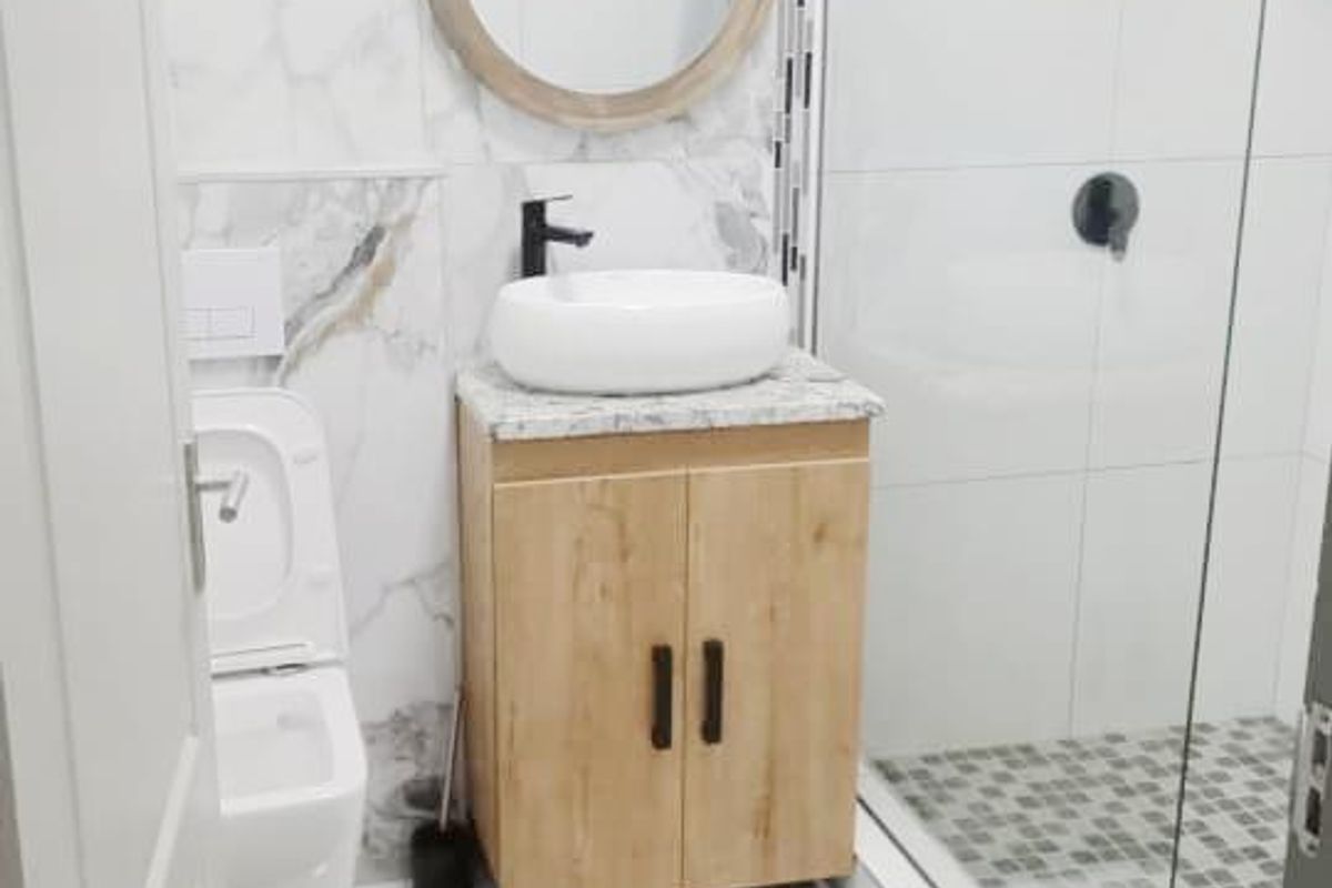 Modern bathroom featuring a walk-in shower with glass screen, wall-mounted toilet, and a vanity unit with a vessel sink and marble-effect tiling.