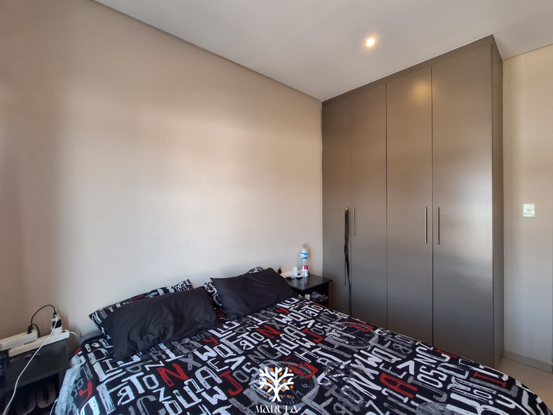 A well-maintained bedroom featuring neutral walls and modern, full-height built-in cupboards providing ample storage space.