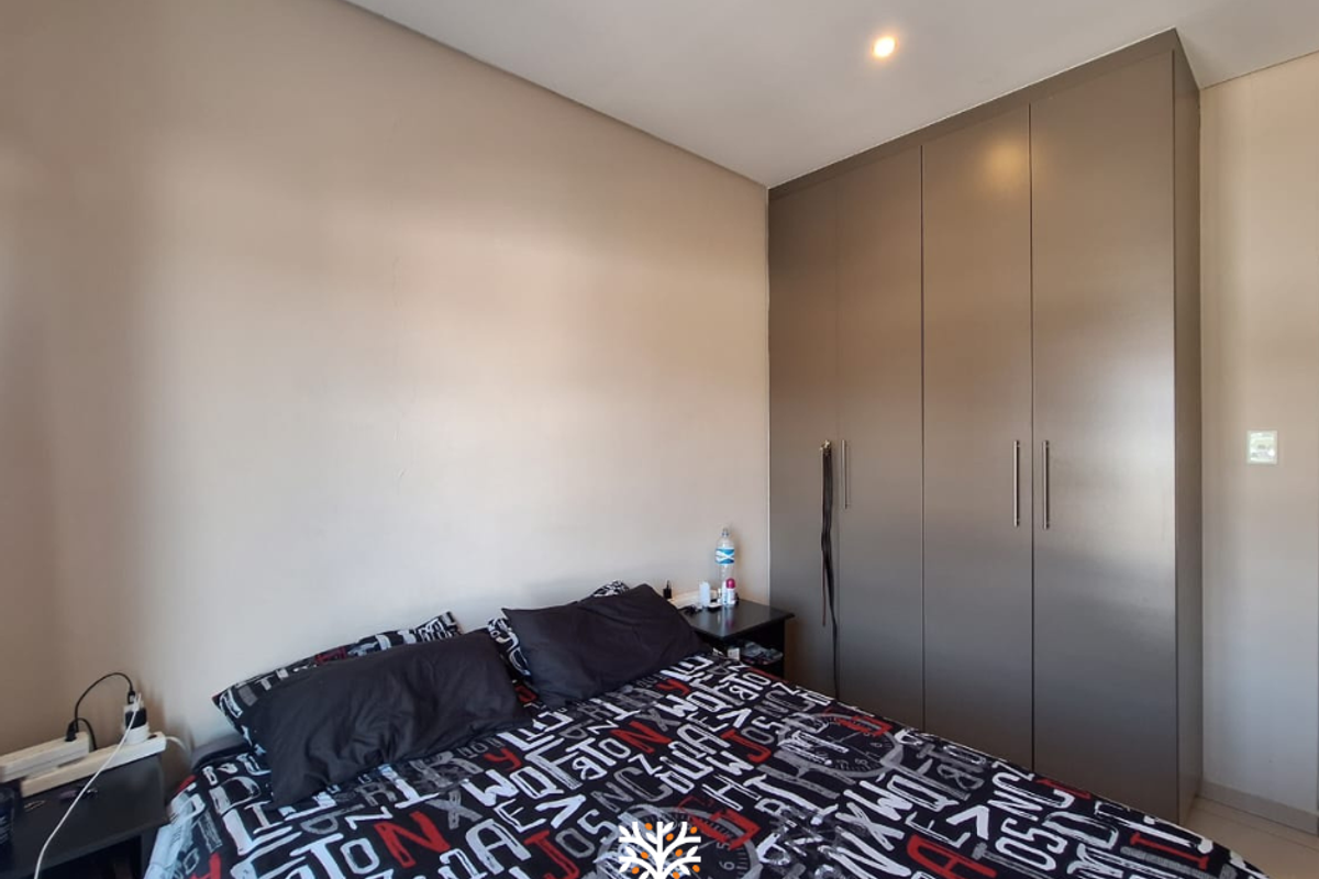 A well-maintained bedroom featuring neutral walls and modern, full-height built-in cupboards providing ample storage space.