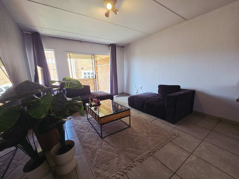 A living room featuring tiled flooring and a sliding glass door providing access to an outdoor area.
