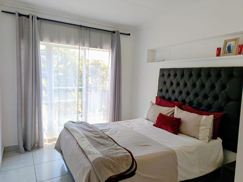 A bright bedroom featuring tiled flooring, a built-in recessed wall niche, and a sliding glass door providing access to an outdoor area.