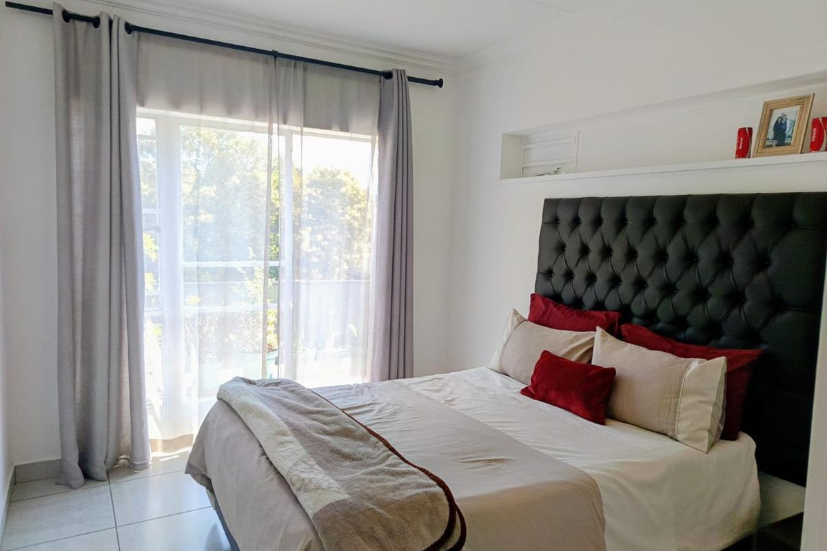 A bright bedroom featuring tiled flooring, a built-in recessed wall niche, and a sliding glass door providing access to an outdoor area.