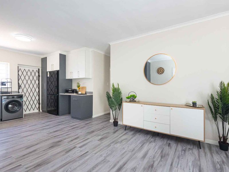 A clean and modern laundry area featuring built-in cabinetry, grey laminate flooring, and a secure external door access.