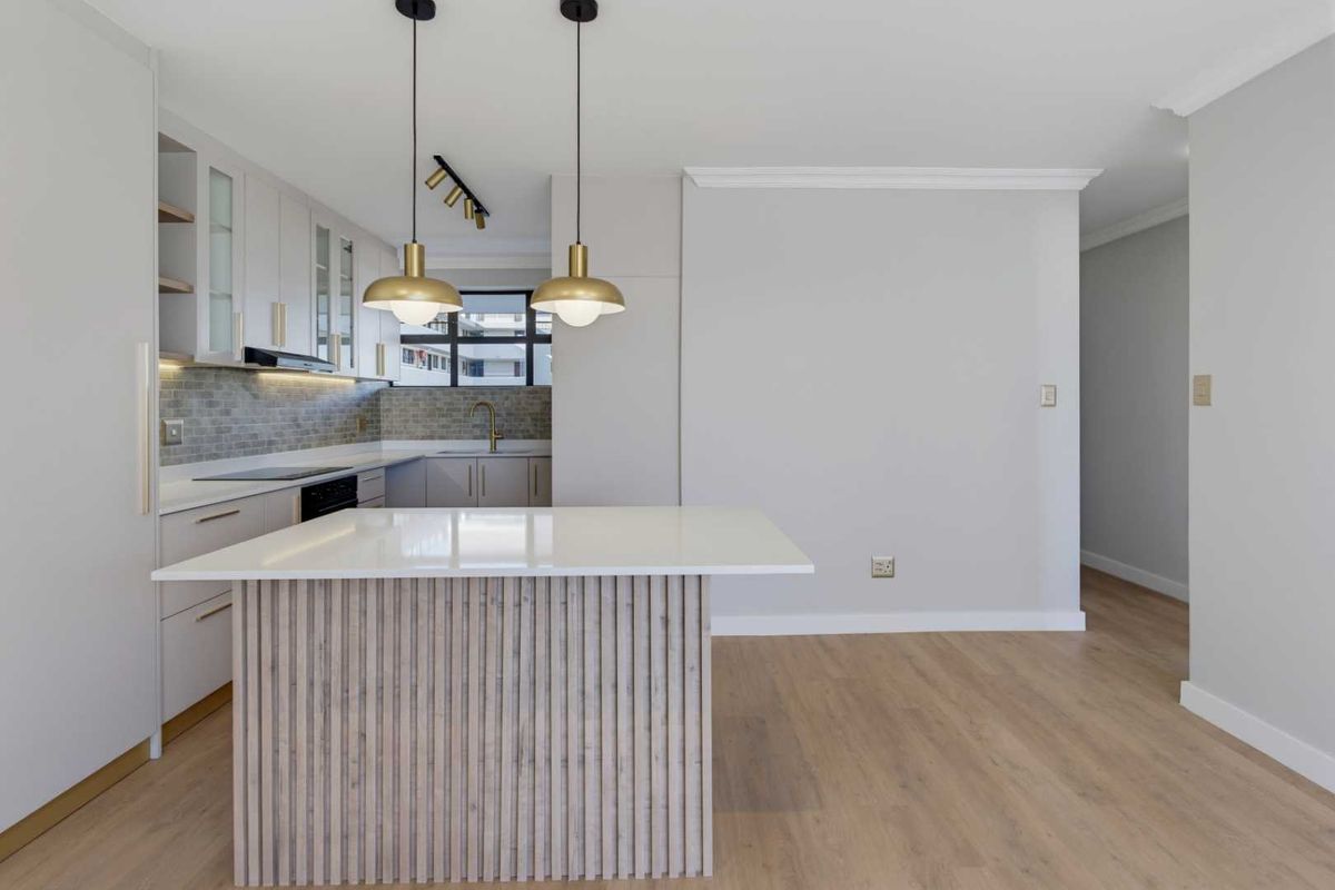 Modern, renovated kitchen featuring a central island with quartz countertop, sleek cabinetry, subway tile backsplash, and high-quality laminate flooring.