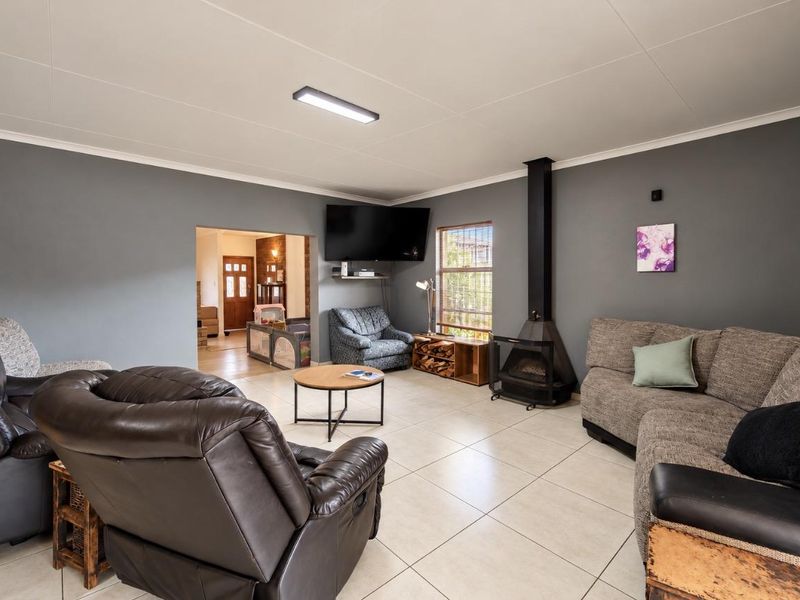 Spacious living room featuring large format floor tiles, a modern freestanding fireplace, and neutral grey walls, offering a comfortable and functional family space.