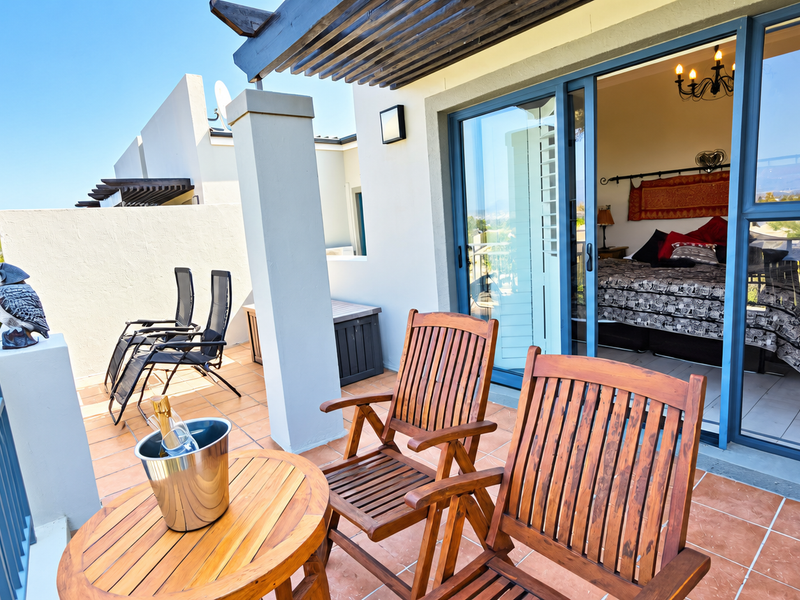 A well-maintained balcony featuring tiled flooring, a pergola, and sliding glass doors providing seamless access to the interior bedroom.