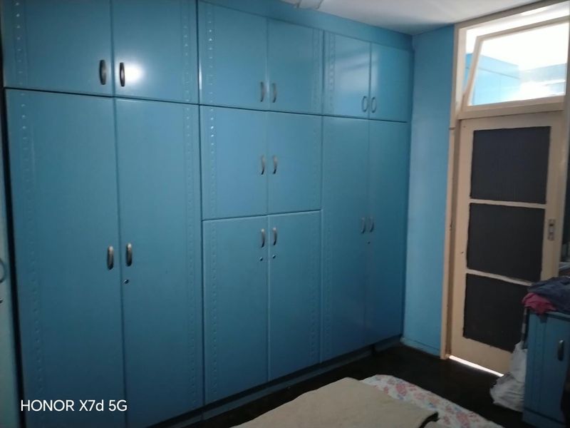 Bedroom featuring extensive floor-to-ceiling built-in cupboards with blue cabinetry and a standard hinged door leading to an adjacent space.