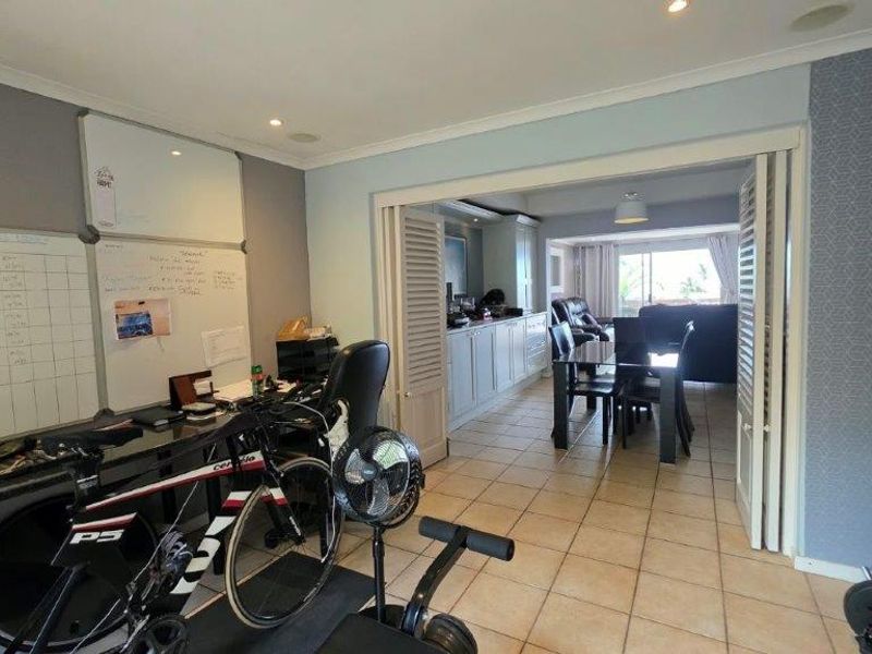 Open plan living area featuring tiled flooring, recessed lighting, and bi-fold doors connecting to an adjacent dining and kitchen space.