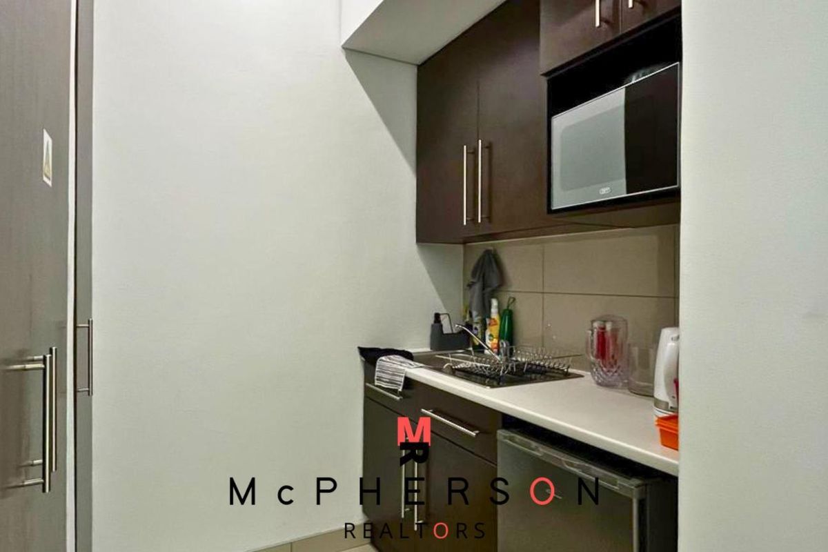 Compact kitchenette area featuring dark wood cabinetry, built-in microwave, and a small countertop workspace.