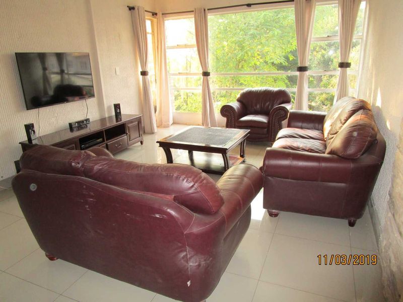 A living room featuring large windows that provide natural light and tiled flooring throughout the space.
