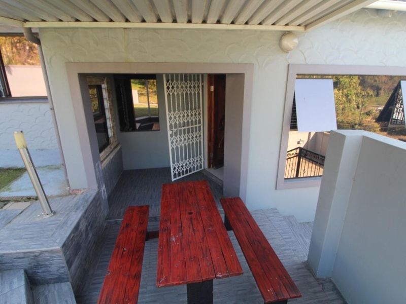 A covered outdoor patio area featuring tiled flooring, a security gate entrance, and exterior wall lighting, providing a functional space for outdoor relaxation.