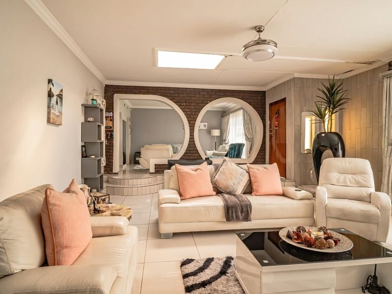 Spacious living room featuring a unique brick wall with circular archways, tiled flooring, a ceiling fan, and a skylight for natural illumination.
