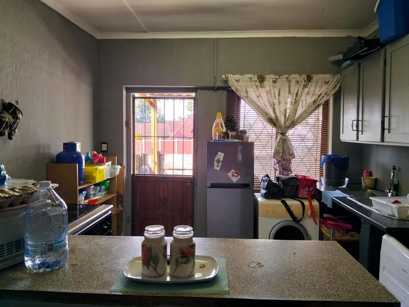 A functional kitchen featuring laminate countertops, built-in cabinetry, and a rear access door with security gate, offering potential for modernization.