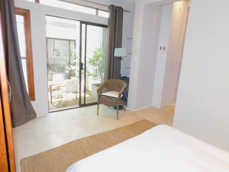 A bright bedroom featuring a sliding glass door with direct access to a private patio area and built-in storage.