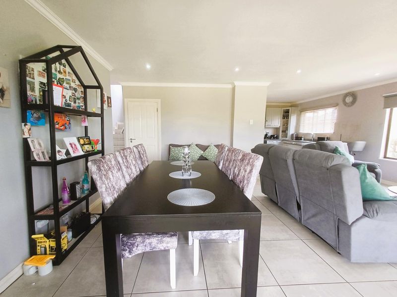 An open-plan living and dining area featuring tiled flooring, recessed lighting, and a connected kitchen space with built-in cabinetry.