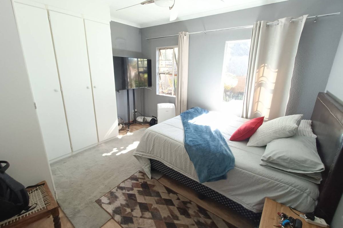 A bedroom featuring built-in wardrobes, a ceiling fan, and natural light from two windows.